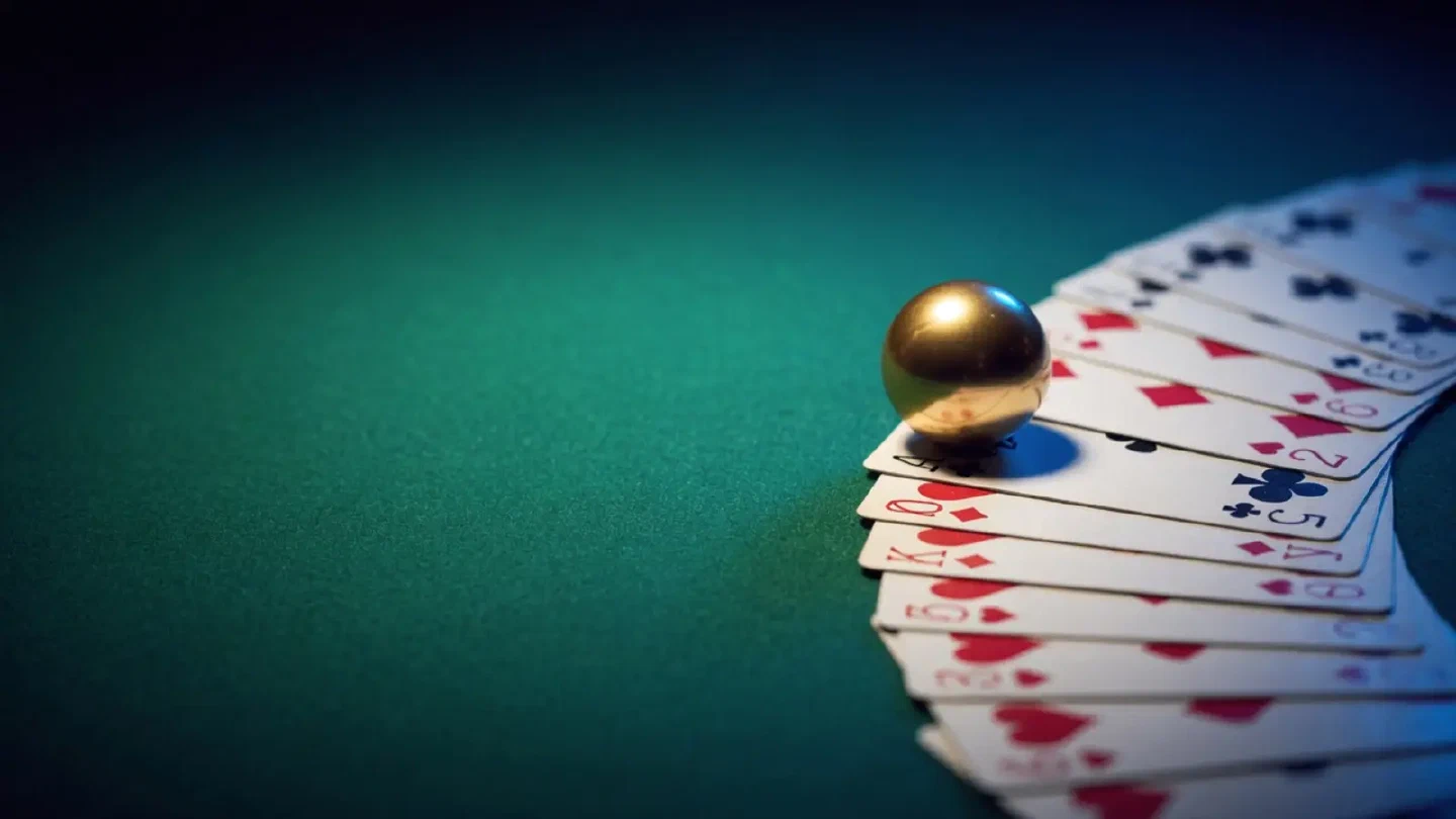 Spieltisch mit Roulettekugel und Blackjack-Karten in blau-goldenem Licht